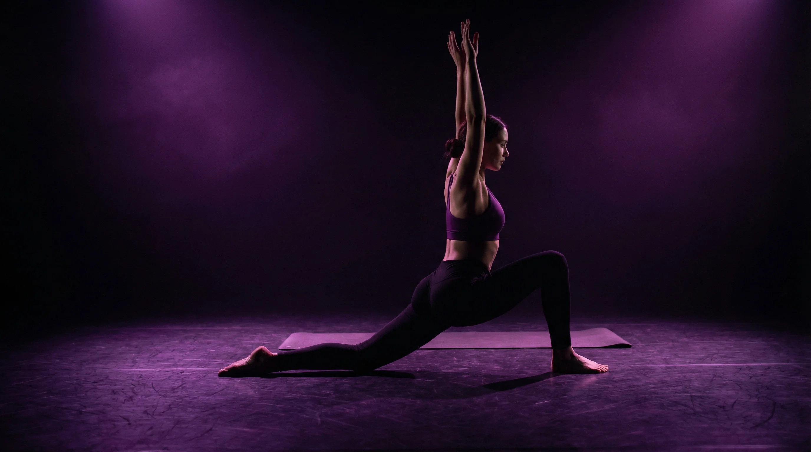 Dancer performing a deep low lunge stretch on a dark studio floor as a warm-up for splits training, Surfers Paradise Gold Coast